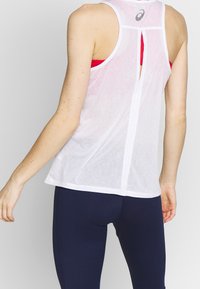 Canotta sportiva bianca realizzata in tessuto leggero, con inserto tagliato sulla schiena, design a racerback e dettaglio discreto del logo vicino al collo.