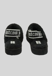 Pantofole nere con texture soffice, schiena aperta e una larga fascia bianca con il logo "justcavalli" in nero, montate su una suola spessa.