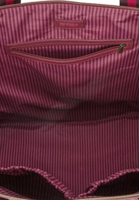 Bordeaux stoffen draagtas interieur met verticale strepen; omvat een ritszak en een logo-label. Getextureerde voeringdetails zichtbaar.