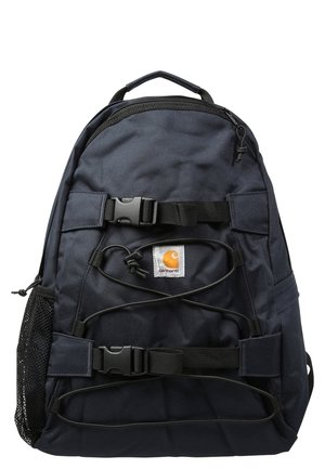 Sac à dos noir Carhartt avec deux sangles à boucles, cordons élastiques à l'avant, une poche latérale en filet et une poignée supérieure pour le transport.