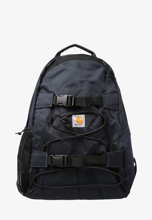 Sac à dos noir Carhartt avec deux sangles à boucles, cordons élastiques à l'avant, une poche latérale en filet et une poignée supérieure pour le transport.