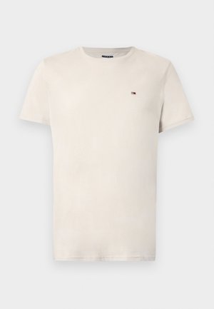 Kortärmad, rundhalsad t-shirt i ljusbeige bomull med en liten logga på bröstet. Mjuk textur och klassisk passform.