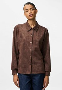 Brun, mockasinsliknande skjortjacka med krage, knappstängning och långa ärmar; har en slät textur, lätt design och subtil lyster.