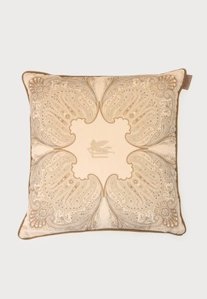 Coussin carré beige avec des motifs cachemire ornés en tons dorés et un dessin central de griffon, bordé d’un passepoil marron.