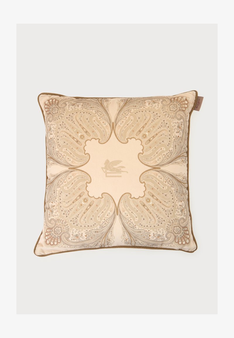 Coussin carré beige avec des motifs cachemire ornés en tons dorés et un dessin central de griffon, bordé d’un passepoil marron.