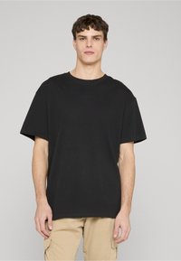 Fekete, rövid ujjú pamut póló kerek nyakkivágással. Laza szabású és sima textúrájú. Egyszerű design, minták nélkül.