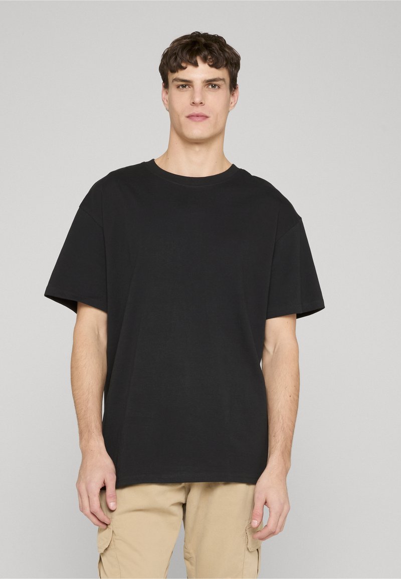 Fekete, rövid ujjú pamut póló kerek nyakkivágással. Laza szabású és sima textúrájú. Egyszerű design, minták nélkül.