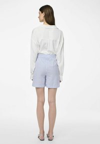 Chemise blanche à manches longues avec un détail de empiècement au dos, associée à un short rayé bleu et blanc doté d'une taille élastique et d'une coupe décontractée.