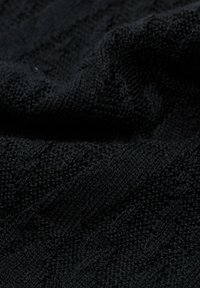 Tessuto a maglia nero caratterizzato da un motivo testurizzato con linee diagonali, che presenta una superficie morbida e leggermente sollevata.