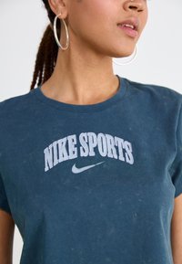 Dark blue cotton t-shirt with a crew neckline, featuring white "NIKE SPORTS" text and logo in a curved design. Subtle texture details visible.