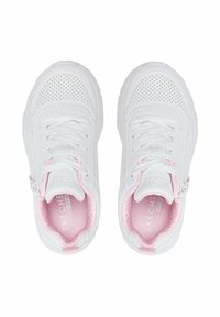 Un par de zapatillas blancas Skechers con punteras perforadas, plantillas acolchadas rosas, cordones y cremalleras en los laterales sobre un fondo blanco.