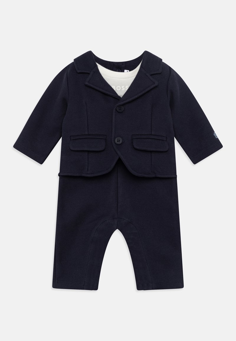 Navyblauw babypak met een colbertachtige jas, voorzien van revers en zakken, gecombineerd met lange broek. Zachte, gebreide stof.