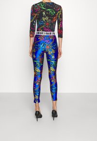 Bodysuit de patrón multicolor con mangas largas, que presenta una base negra, diseños vibrantes y leggings azules con acentos elaborados.
