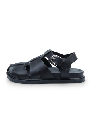 Black leather sandal with an open-toe design, adjustable strap, and flat sole. Features crisscrossed straps for ventilation and comfort.