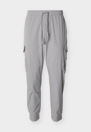 Pantalon cargo gris clair avec taille élastique, cordon de serrage, poches latérales à rabat et chevilles resserrées.