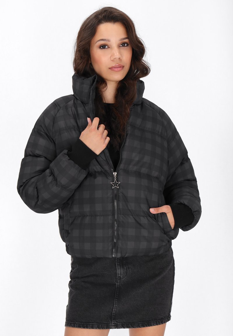 Černá kostičkovaná péřová bunda s kapucí a předním zipem, s hvězdicovým táhlem zipu. V kombinaci s černou džínovou sukní.