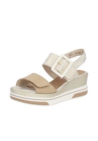 Sandale compensée beige et dorée avec une large bride devant, une sangle métallique à la cheville et une grande boucle carrée sur fond blanc.