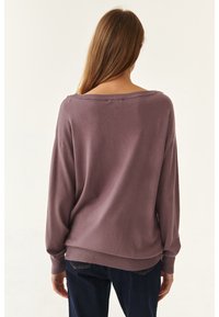 Maglione overdimensionato in viola tenue, caratterizzato da un ampio scollo e polsini a coste. Tessuto morbido, vestibilità comoda, con elementi di design minimalisti.