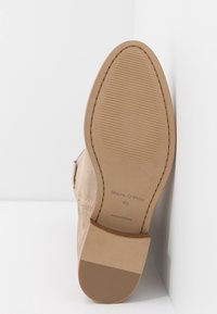 Bottine en suede beige avec une semelle lisse, présentant une texture striée pour l'adhérence et un détail de couture au niveau du talon. Marque : Marc O'Polo.