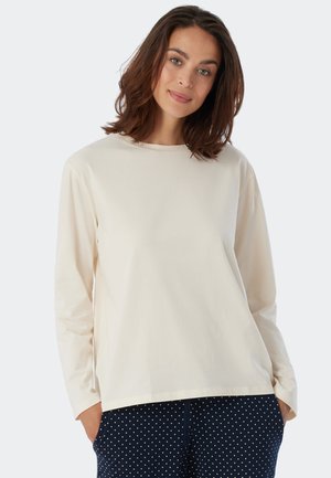 Långärmad, krämfärgad T-shirt i mjuk bomull. Avslappnad passform med rund halsringning, kombinerad med prickiga byxor.