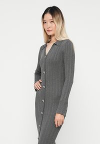 Γκρίζο ριγέ φόρεμα με μακριά μανίκια, γιακά και κούμπωμα με κουμπιά μπροστά. Διαθέτει διακοσμητικά κουμπιά και εφαρμοστή σιλουέτα.