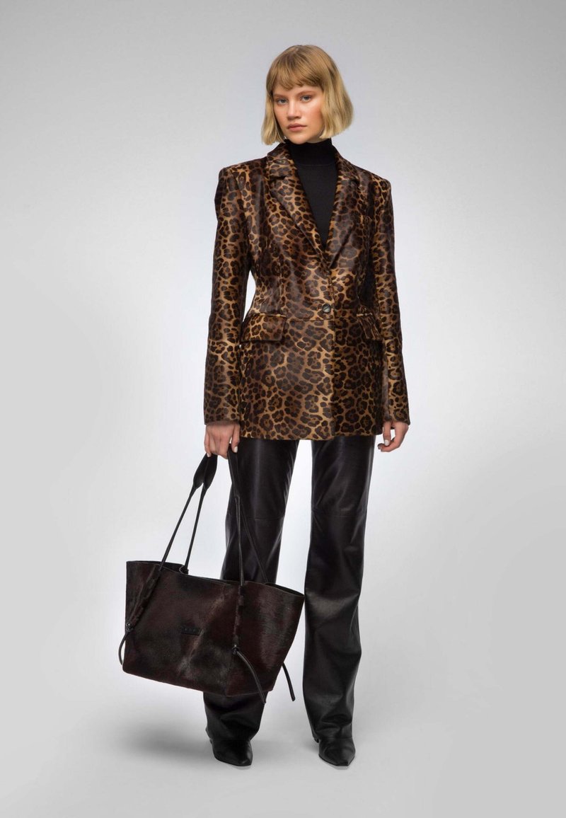 Leopard print blazer in shiny fabric, paired with black leather pants and a large black tote bag with dual handles.
