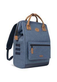 Blauwe stoffen rugzak met bruine leren accenten, verticale rits aan de voorkant, textuur op de buitenkant en gepadde schouderbanden.