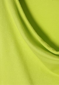 Tessuto di un luminoso verde lime con una superficie liscia, caratterizzato da morbide pieghe e un leggero lucore, adatto per il design di abbigliamento.