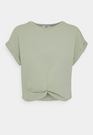 Lys grøn cropped t-shirt lavet af blødt bomuld. Har korte oprullede ærmer og et snoet design ved sømmen foran. Glat tekstur hele vejen igennem.