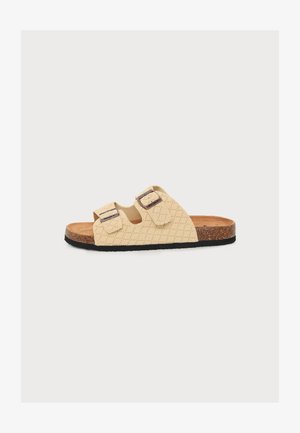 Sandale beige à enfiler avec deux brides ajustables, semelle en liège marron et semelle en caoutchouc noire.