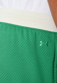 Zaļie acs šorti ar baltu elastīgu jostu; sānos ir Under Armour logo atbilstošā zaļā krāsā; elpojošs audums ar perforācijām.