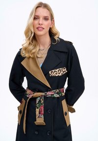 Czarny płaszcz trencz z brązowymi akcentami, kieszenią w panterkę i kwiatowym paskiem. Posiada dwurzędowe guziki i naramienniki.