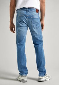 Vaqueros de denim azul claro con un diseño de pierna recta, que cuentan con dos bolsillos traseros y un parche de cuero marrón en la cinturilla.