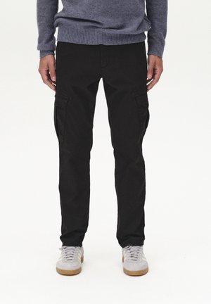 Black cargo pants with side pockets, made from durable material, paired with light gray sneakers and a textured blue sweater.
