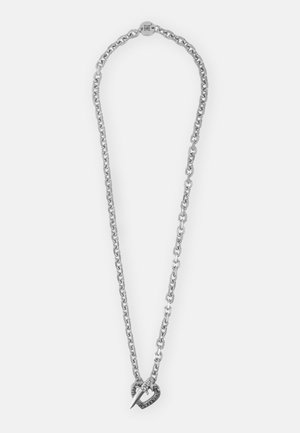 Collar de cadena de plata con un colgante en forma de corazón con punta afilada, adornado con pequeñas piedras negras, acabado suave y diseño audaz.