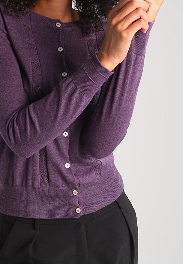 Lila stickad cardigan med rund halsringning, knappstängning och detaljerad sömnad på axlarna. Långa ärmar och figurnära design.