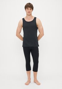 Black tank top and black three-quarter leggings, made of soft, stretchy fabric. The outfit has a fitted design with no visible patterns or accents.