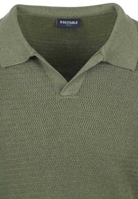 Olivgrünes Polohemd mit strukturiertem Strickmuster, V-Ausschnitt und klassischem Kragen. Markenetikett "Suitable" innen sichtbar.