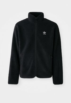 Black fleece jacket with high collar, zip front, and front pockets. Features textured fabric and small white logo on left chest.