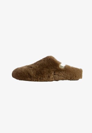 Zapatilla marrón de peluche con una textura suave, diseño de tipo slip-on, punta redondeada y una sutil etiqueta de marca en el lateral.