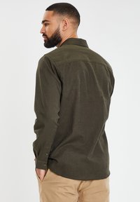Donkergroen langemouwen overhemd met een button-down kraag, textuurstof en knoopmanchetten. Perfecte pasvorm met een gebogen zoom.