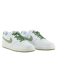 Weiße Sneakers mit grünen Akzenten, aus Leder gefertigt. Merkmale sind eine perforierte Zehenbox, flache Schnürsenkel und eine Gummisohle. Einfaches und klassisches Design.