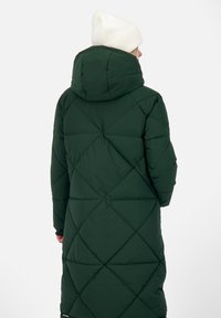 Lång grön puffjacka med diamantquiltat mönster, hög krage och avtagbar huva. Har en slät, matt textur och elastiska manschetter.