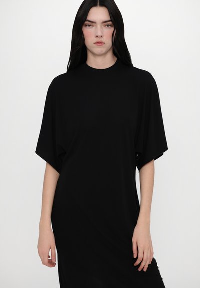 Robe noire ample avec des manches courtes et larges et un col haut, en tissu lisse, présentant un design minimaliste.