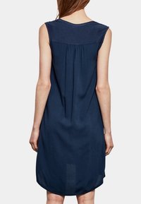 Marineblaues ärmelloses Kleid mit runder Ausschnitthöhe, das über ein gerafftes Rückendetail und einen lockeren Schnitt verfügt. Glattes, leichtes Material.