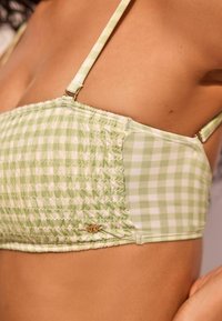 Zöld kockás bikini felső smocking hatással, állítható pántokkal és aranyszínű részletekkel.
