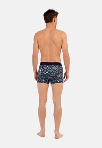 Bóxer para hombres con un diseño oscuro y estampado que presenta coloridos motivos tropicales. Cintura elástica, ajuste ceñido, largo hasta mitad del muslo.