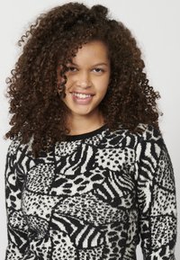 Czarny i biały sweter robiony na drutach w wzory, z abstrakcyjnymi motywami, długimi rękawami, okrągłym dekoltem i miękką teksturą.