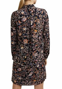 Blommönstrad klänning i mörk marin, med långa ärmar, en krage och rak skärning. Tillverkad av lätt, slät tyg med en lätt lyster.