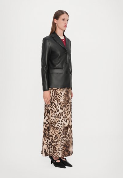 Black faux leather blazer, single-breasted with two buttons, paired with a long beige leopard print satin skirt and pointed black heels.